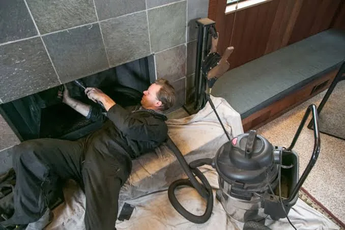 Chimney technician performing careful fireplace maintenance with professional equipment